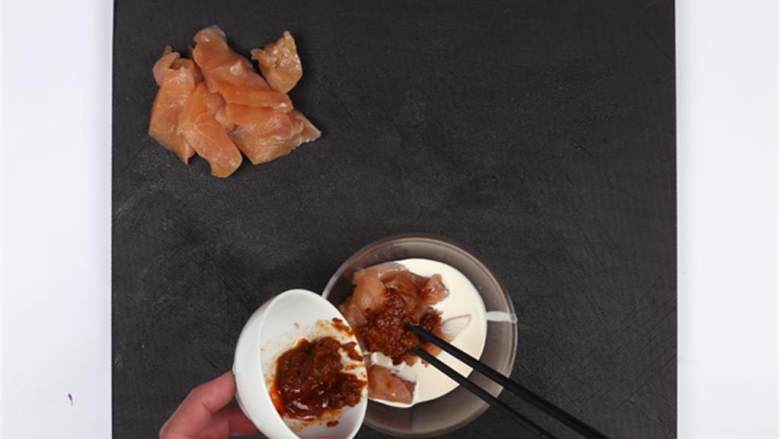 意式水牛芝士配叻沙鸡肉,将鸡胸肉 从中间切成两块,再将鸡胸肉切0.5cm的薄片;在鸡胸肉中倒入叻沙辣椒酱 和椰浆 搅拌均匀,腌制15分钟。
