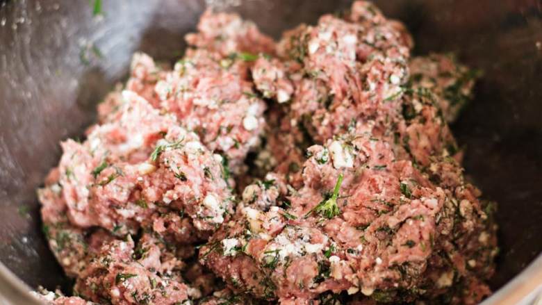 希腊烤羊肉皮塔三明治,在一个大碗里，用手混合羊肉糜 ，切碎的新鲜牛至 ，一半的莳萝碎，粗海盐 和切碎的菲达芝士