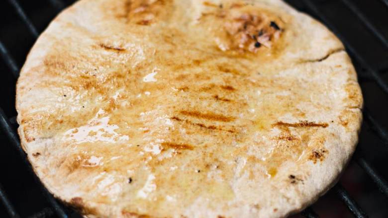 希腊烤羊肉皮塔三明治,在皮塔饼 上刷一层橄榄油 ，然后把饼放在煎锅或者烤箱里稍稍烘烤一下。