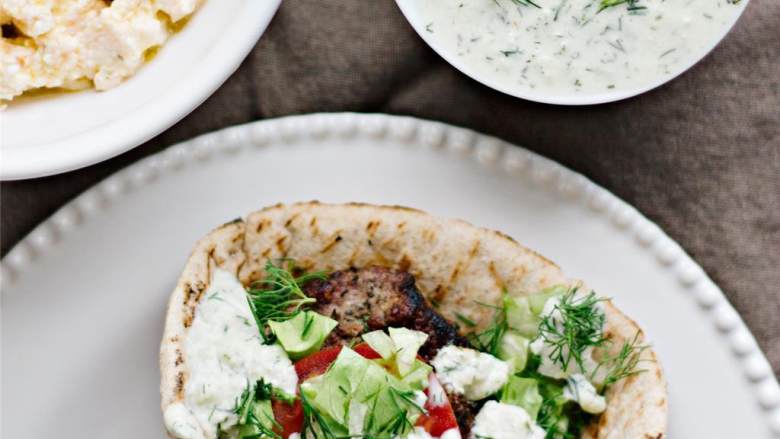 希腊烤羊肉皮塔三明治,现在来做三明治吧——在皮塔饼中间放一块羊肉饼，盖上切片番茄，卷心莴苣碎和剩下的莳萝，再加几勺希腊酸奶黄瓜酱和希腊菲达芝士蘸酱（Tirokafteri）。如果你愿意，还可以加上辣酱哦。