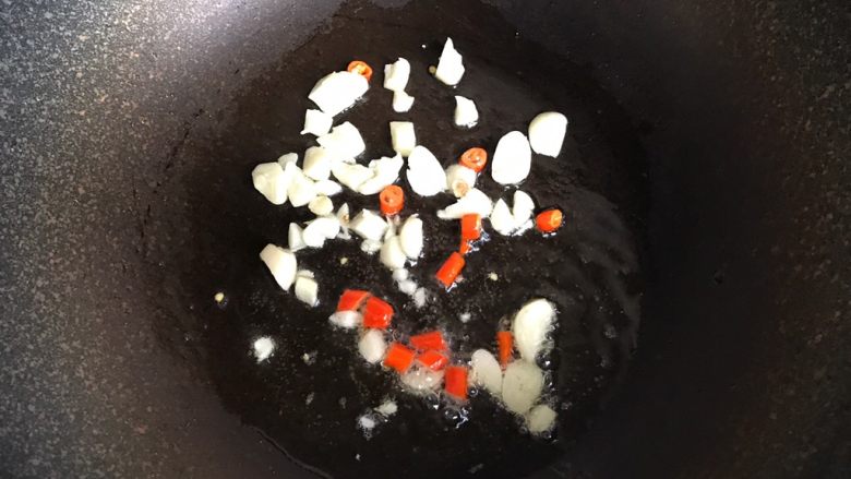 酸辣土豆丝,锅中倒入适量油,放入大蒜和小米椒炒香