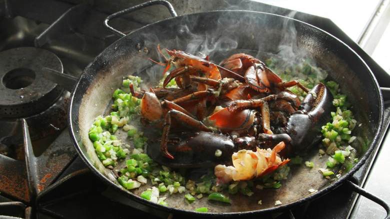 波士顿龙虾海鲜饭,加入龙虾,煮至出水。龙虾变色后,舀出,但是龙虾头还是留在锅里。