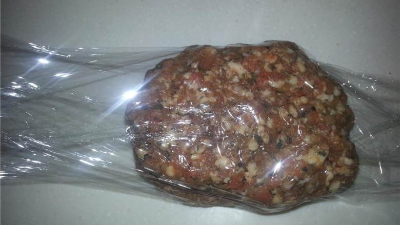 自制田园风香肠,用保鲜膜把一小团猪肉碎包起来,如图所示,揉搓到圆柱形,这样你做汉堡肉的时候方便切片。