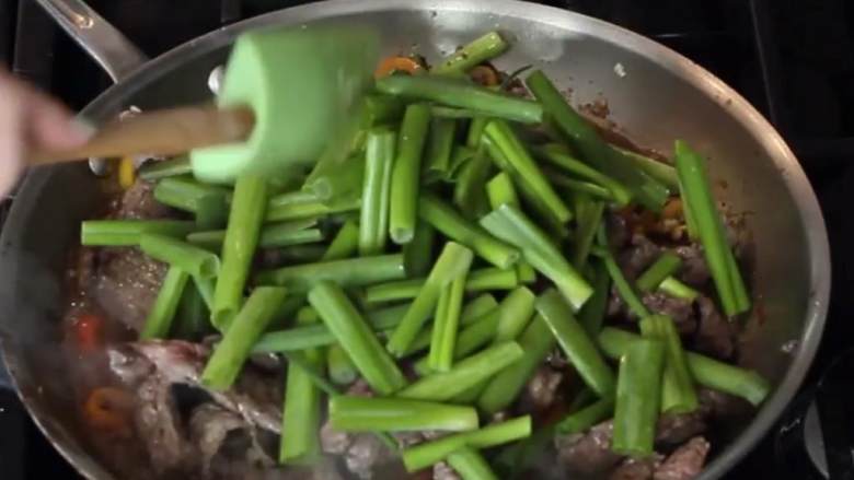 葱炒牛排饭,当酱油冒泡时,放入牛排和葱叶。
