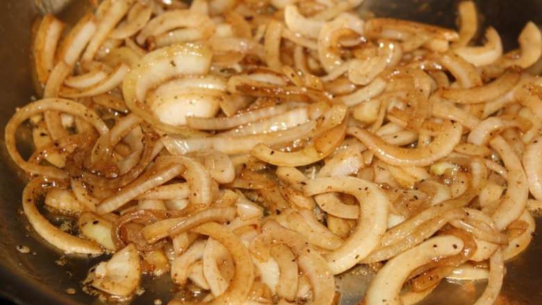 洋葱炒蘑菇,大平底锅中火加热，加入糖和一汤匙的黄油。融化后加入洋葱，翻炒至洋葱半透明。调到小火，偶尔翻炒防止粘锅。