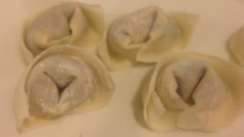 高汤馄饨,用牛奶或者蛋清涂在皮的四周,向上对折,压紧。