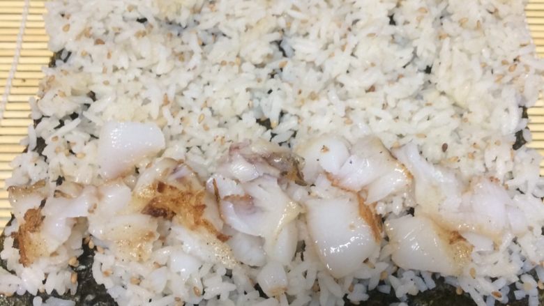 鳕鱼肉松寿司,把拌好的米饭铺在海苔上铺平,最好用勺子轻轻压一下,最下边一头放入一排鱼肉块