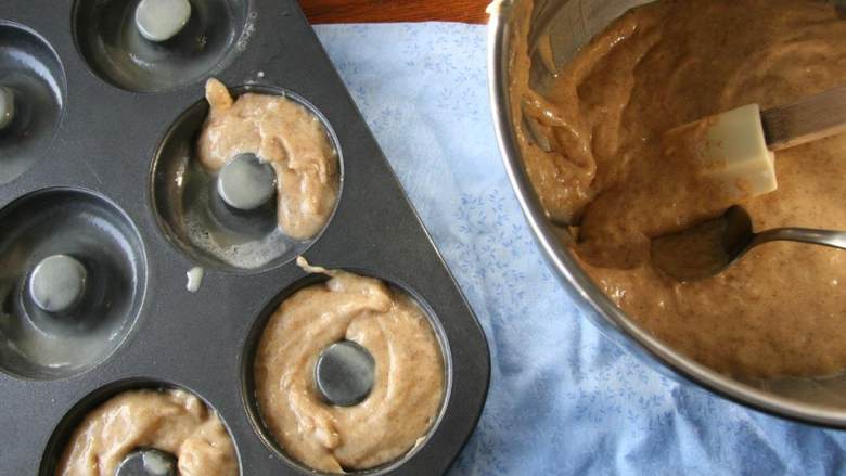 烤香蕉甜甜圈,将面糊倒入涂了油的甜甜圈模具里，大约倒3/4满。烘烤12分钟。烤完放在架子上直到完全冷却下来。