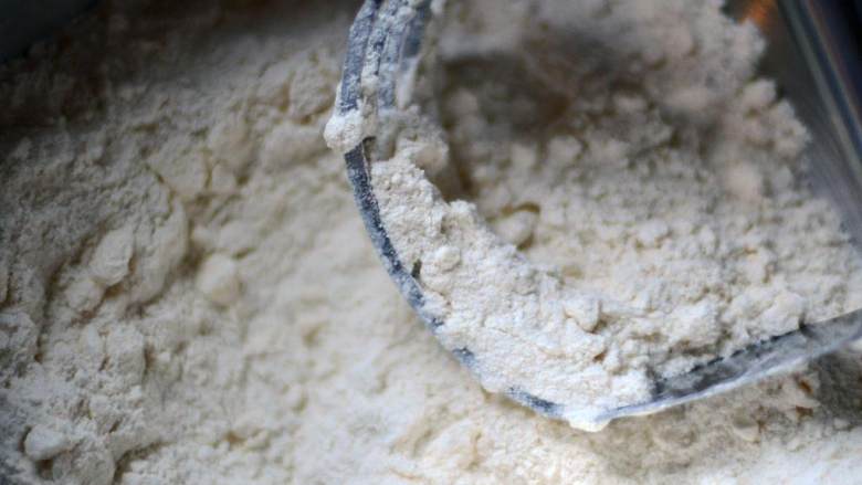 蔓越莓橙子核桃面包,把中筋面粉、砂糖、泡打粉、盐倒入大碗里搅拌均匀。