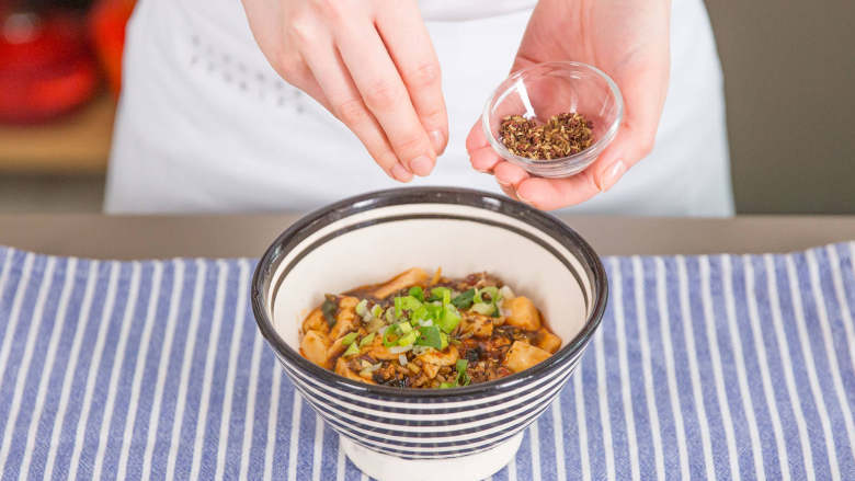 麻婆豆腐,盛到餐盘中，依喜好撒上四川花椒面和青葱。开始享用吧！