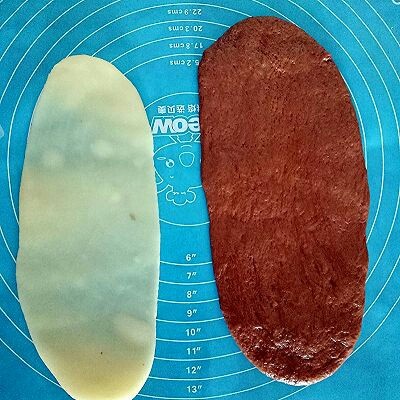 可可麻薯软欧包,取一个发酵好的面团擀成椭圆形,取一份麻薯擀成比面团稍微小些的椭圆形