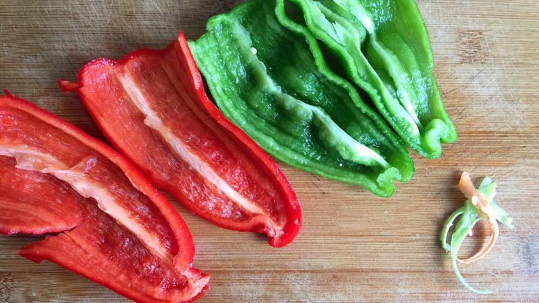 五彩土豆炒牛肉,浸泡牛肉期间，切青红椒，对半切开，撕去筋膜