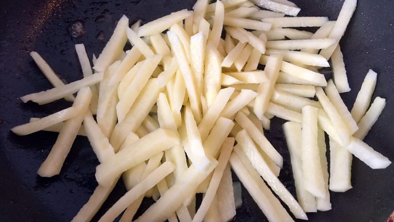 五彩土豆炒牛肉,油热后倒入沥干水份的土豆