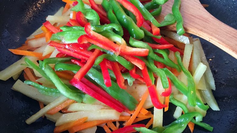 五彩土豆炒牛肉,将青红椒放入