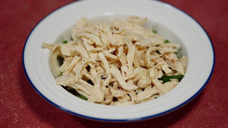 香辣秋葵手撕鸡,将秋葵铺在盘底,将浸过凉水的鸡肉,随意撕成条状,覆盖在秋葵之上,和腐竹混合在一起