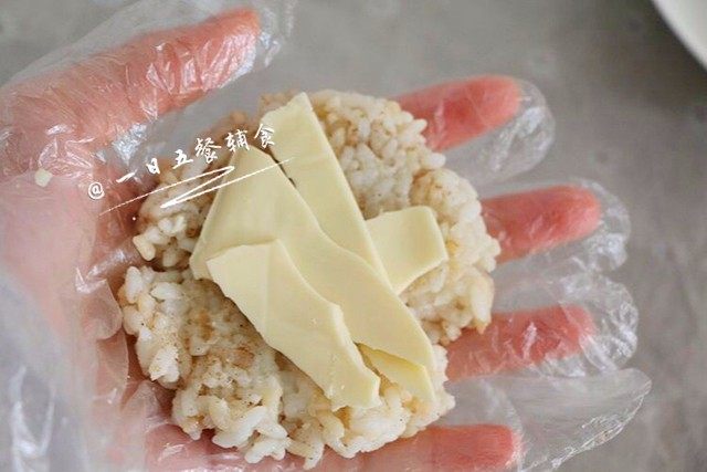 芝士蛋煎饭团,手掌上放一勺米饭,把米饭推平至饼状,芝士放入中间。(我一片芝士包了两个饭团)