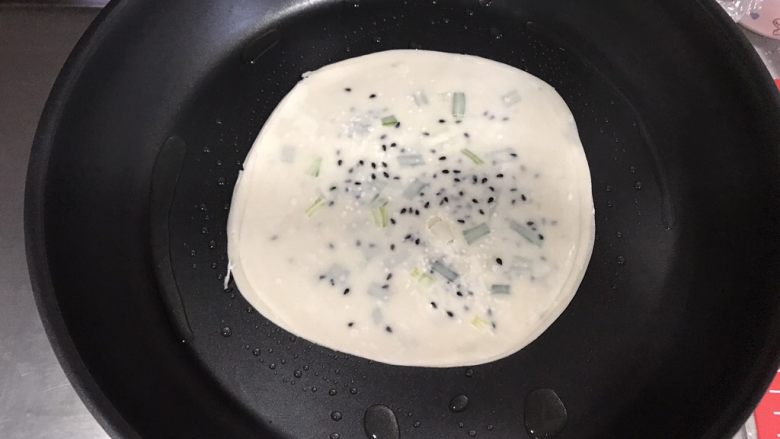 香酥葱油饼,葱油饼放入平底锅,用筷子不断翻动使受热均匀