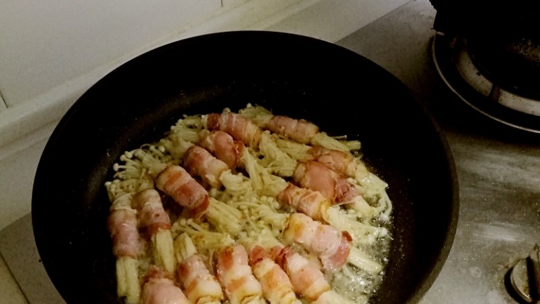 培根金针菇卷,金针菇没挤得那么干(慢慢煎出了好多水)，还出了好多油(培根有点肥)，只好开大火啦!水收得差不多了就用手指撒点<a style='color:red;display:inline-block;' href='/shicai/ 720'>胡椒粉</a>，<a style='color:red;display:inline-block;' href='/shicai/ 146542'>孜然粉</a>