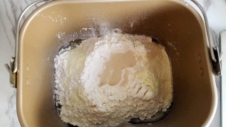 香葱火腿包,面包机揉面,将面包食材部分按照先液体再粉末的顺序投入面包机里,揉面至扩展阶段,