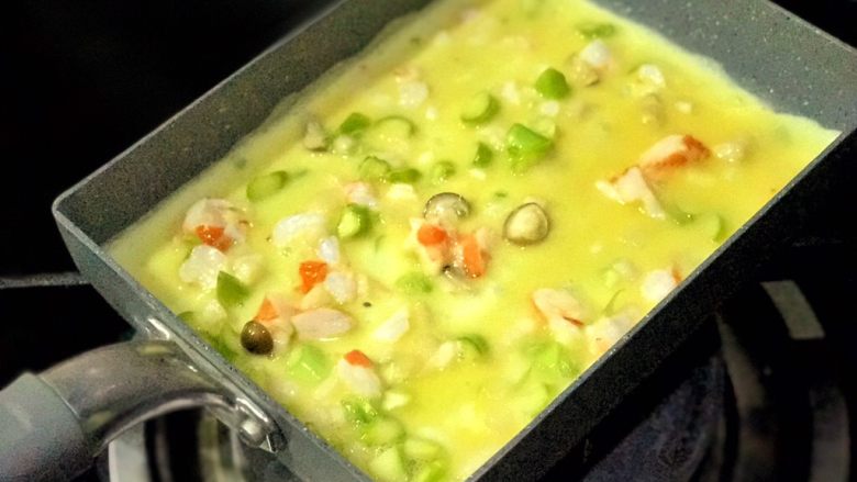 幸福满满厚蛋烧(宝宝辅食),然后将都是料的那碗蛋液下锅,前后左右摇匀,让蛋液和食材均匀分部在锅底。