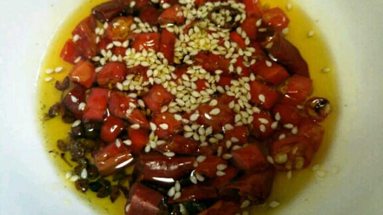 凉拌麻辣鸡架,另起锅留油,这个油量可以适当多一将其倒入放红干椒和麻椒的碗中,并将芝麻撒入~