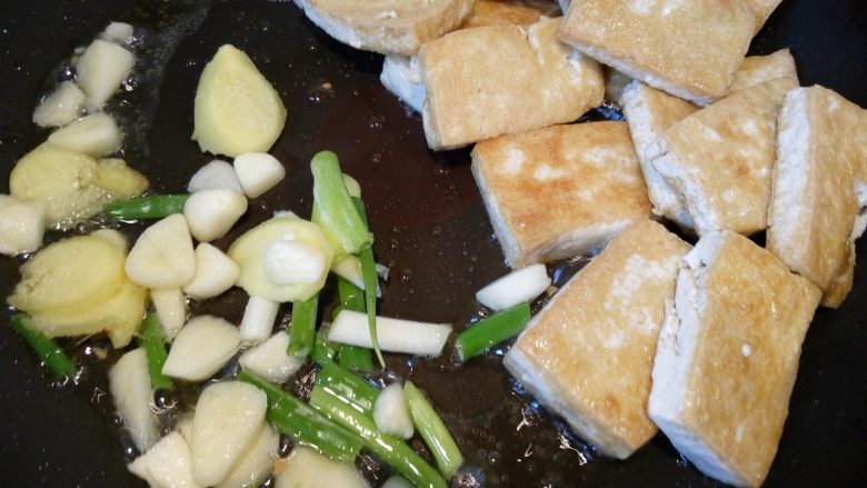 菌茹烩豆腐,把豆腐推到一边,倒入葱姜蒜等调料。