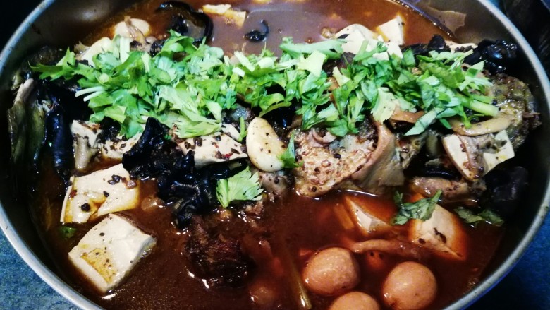 豆豉烤鱼,将汁水淋在鱼身上,撒上花生仁,芹菜叶,放置电磁炉上低温加热。
