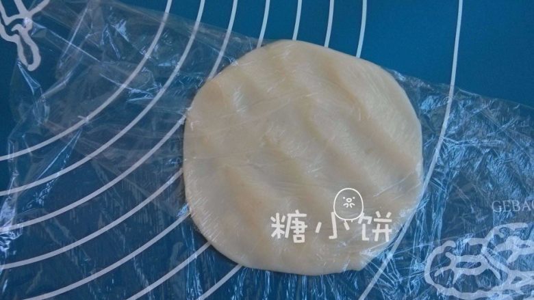 【卡通冰皮月饼(椰香奶黄馅)】超级懒人法,取一个冰皮面团,用手压扁或者用擀面杖擀扁。
如图我是用保鲜膜包着压的,这样可以解决很多人担心的粘手问题。