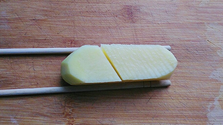 孜然土豆塔,取一双不用的筷子,放在土豆块两边对齐,然后在上面切均匀的斜刀;(借用筷子辅助,土豆就不会切断了)