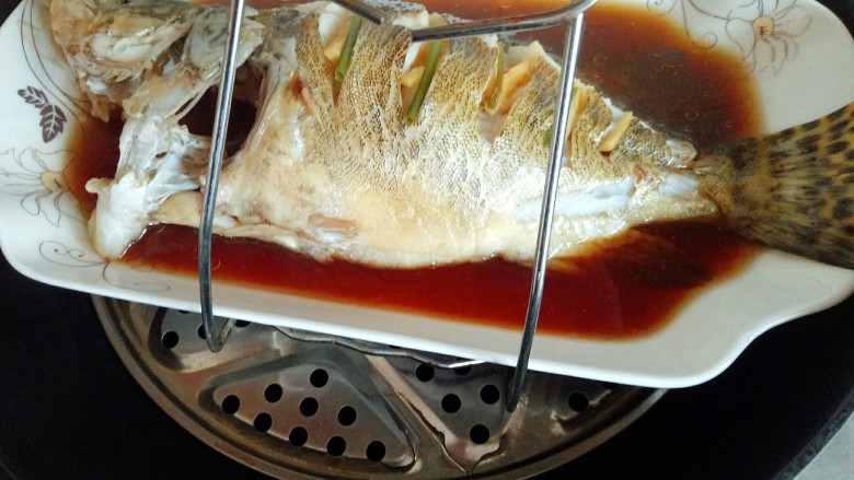 #味道鲜美的#清蒸桂鱼,蒸好的桂鱼,用夹子将盘子夹出,注意烫手。 蒸好的鱼会有很多汤汁,将汤汁倒出,再换个干净的鱼盘。(不换鱼盘也可以,根据个人喜欢。)
