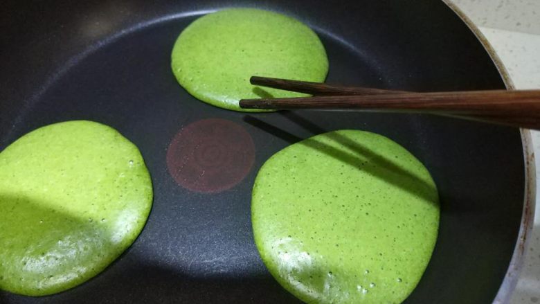 抹茶松饼(低卡、无泡打粉快捷版),等至松饼边圈十厘米的样子面糊煎熟,就是筷子碰触不会粘面糊,而饼的中心依旧会粘到面糊,翻面,