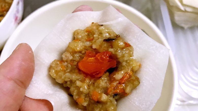 咸蛋黄糯米烧卖,取一片云吞皮放入一勺糯米饭,在中间放咸蛋黄粒