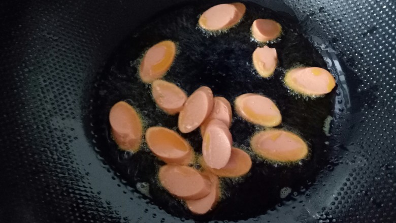 火腿肠炖土豆,油到七分热时,放入火腿肠。翻炒。