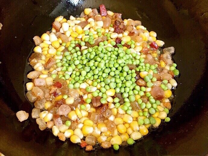 土豆腊肉焖饭,放入玉米粒,豌豆一起翻炒。