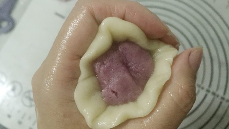 蛋黄千层酥,取一个油皮压扁包一个油酥,包的时候油皮慢慢向中间推,直到完全包住油酥,顶部多余的油皮可以取下来不要。