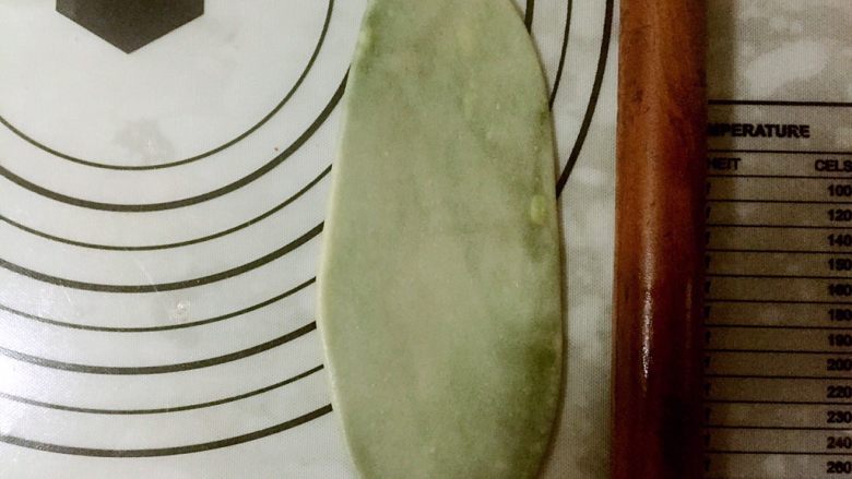 蛋黄千层酥,取一个用擀面杖从中间向两头轻推擀面杖,擀成牛舌状。