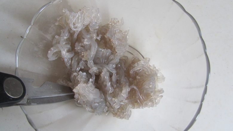 韭菜鸡蛋粉丝包,将煮好的粉丝放入碗中, 用剪刀剪成小段;