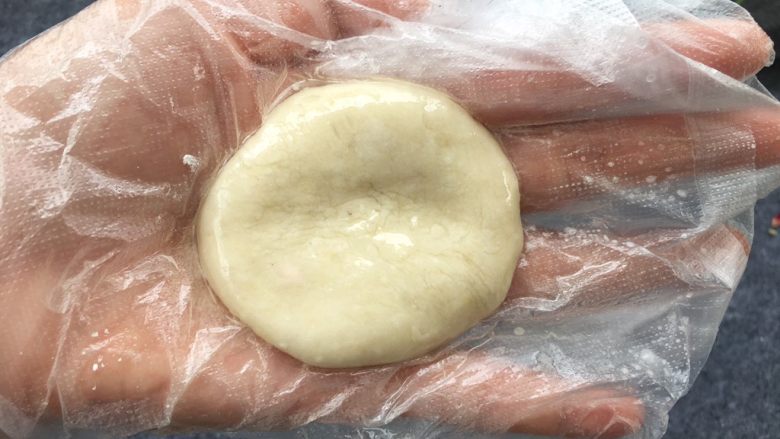 柿子糯米糍,糯米粉凉透后,准备一块保鲜膜或戴上一次性手套,防止粘手。保鲜膜上刷一点点油,把糯米团压扁。