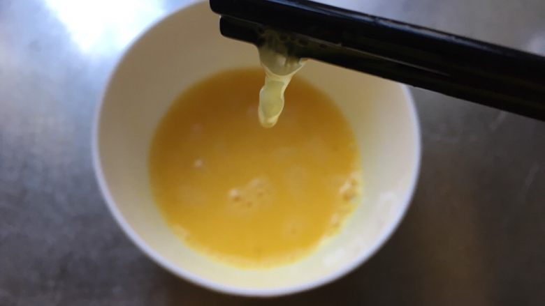 如豆腐脑儿般滑嫩的蒸蛋羹,筷子或者蛋抽等打散鸡蛋,尽量把蛋筋打到越少越好。(图中筷子提起的就是蛋筋。)