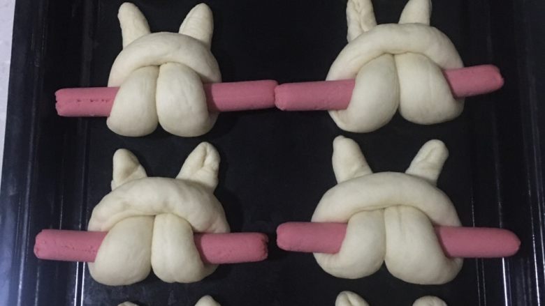 兔子火腿肠面包,均匀地摆放在烤盘里,注意每个之间要留一定空间。再放入烤箱发酵功能下开始二发,边上放一盆热<a style='color:red;display:inline-block;' href='/shicai/ 156925'>水</a>,保持湿度。
