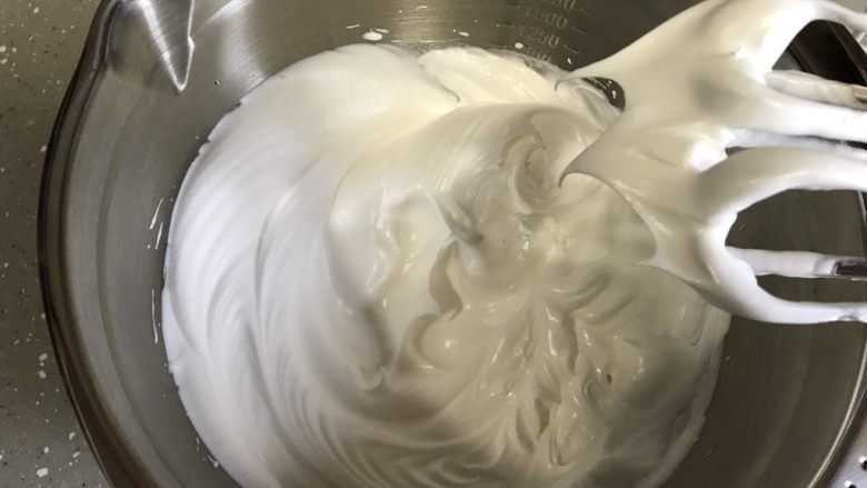 柠檬甜甜圈,高速打发至提起打蛋头出现直立小尖勾,转低速继续打发几分钟整理一下蛋白霜。