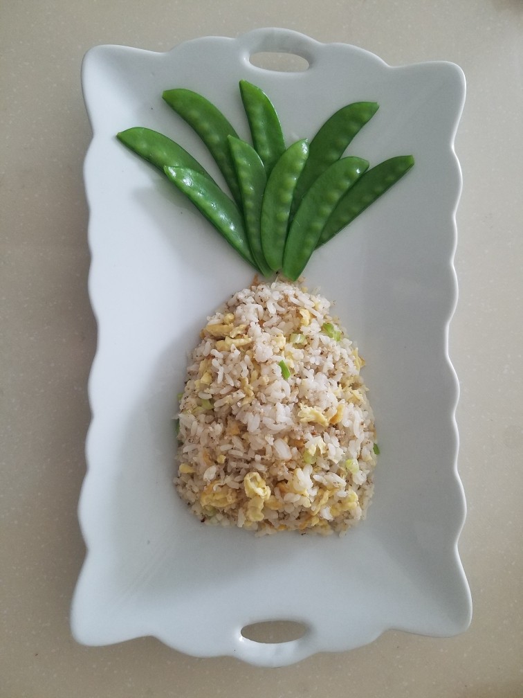 菠萝蛋包饭,炒好的米饭盛到盘子里,用勺子整形成菠萝的形状,上窄下宽。