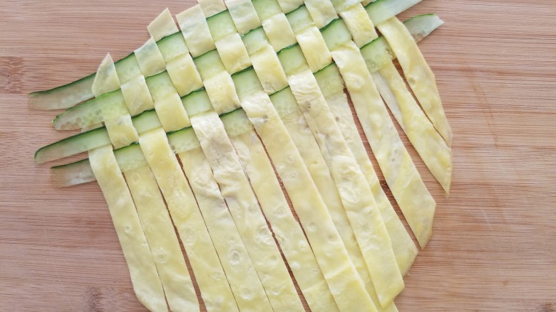 菠萝蛋包饭,然后把蛋条放下,错开上一排继续间隔一个揭起鸡蛋条再放入黄瓜条。