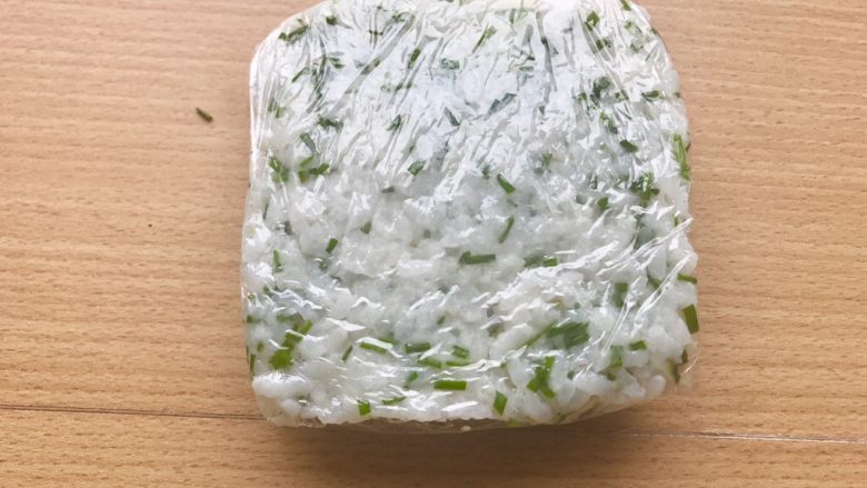 香甜米饭-葱香粢饭糕,第二天一早醒来,将容器内的米饭用倒扣的形式倒在保鲜膜上,然后包裹起来。如果觉得倒扣米饭下不来,可以轻轻用小刀沿边缘扣几下。