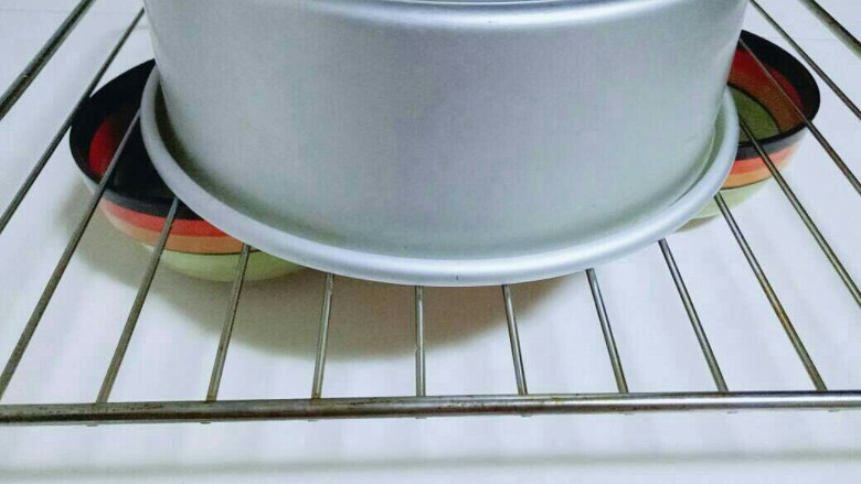 8寸戚风蛋糕,40分钟后戴上隔热手套,取出烤盘,垂直摔一下,震出热气。即可倒扣再烤网上,下面可以放两个碗,这样凉的比较快,彻底凉后再脱模。