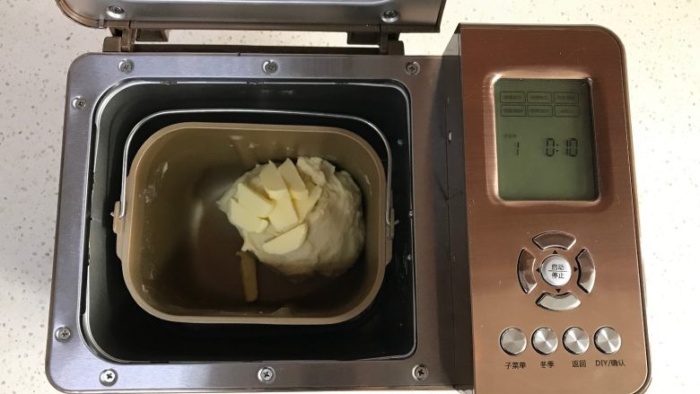 面包机版红枣果仁面包,加入软化的黄油,继续和面10分钟。