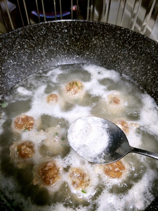 丸子粉丝汤,用勺子撇去浮沫,加入配菜