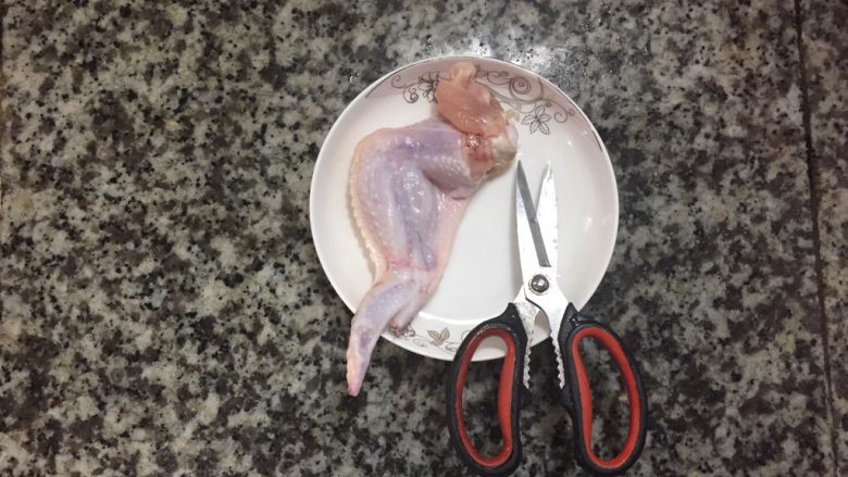 鸡翅包饭,现在把鸡翅去骨,最好用厨房剪刀,这样比菜刀好操作,在鸡翅头上,用剪刀把肉和骨头分离,然后用手把鸡翅的关节骨掰断,这样就很容易取出。注意一点,一定不能把鸡翅皮弄破,这样塞饭时就会漏了
