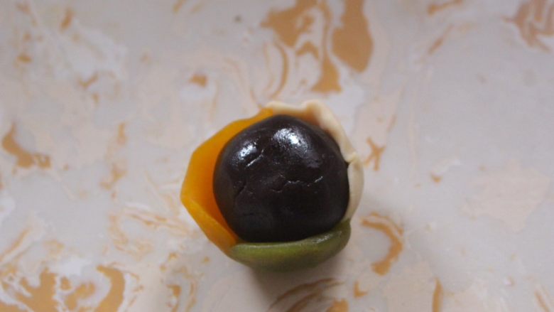 多彩月饼,把豆沙放到皮中间然后包起来,用手的虎口位置慢慢赶压直至完全包住
