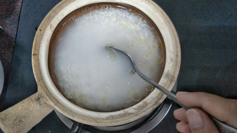 腊肠煲仔饭,把浸泡好的大米沥干水分,加入清水 油混合均匀